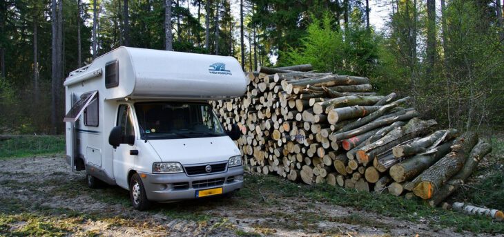 Camper naast houtstapel wildkamperen Camper Deluxe
